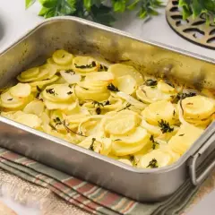 Patatas a lo pobre recién horneadas en una bandeja metálica, con rodajas finas de patata y cebolla doradas y hierbas aromáticas.