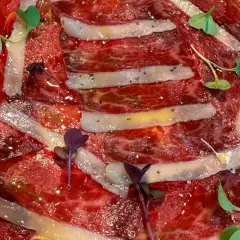 Finas lonchas de jamón ibérico, un manjar de moda, con un toque de pimienta y brotes verdes.