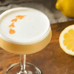 En drink med fluffigt kokosskum och en citronskiva bredvid.