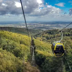 Żółta kolejka linowa z Szyndzielni na Klimczok mija jesienne lasy, a w oddali widać panoramę miasta.