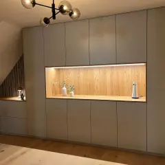 Moderne Einbauschränke gestalten eine gemütliche Schlafnische mit beleuchtetem Holzelement und Deko.