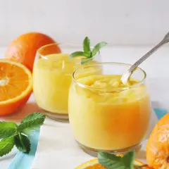 Dwa szklanki orzeźwiającego, gęstego **orange curd** z miętą i świeżymi pomarańczami.