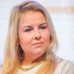 Kamila Kalinczak z blond włosami i złotym naszyjnikiem, patrzy w bok.