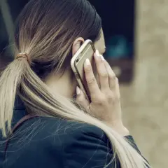 Kobieta z blond kucykiem rozmawia przez telefon, planując urlop na żądanie.