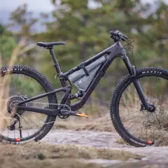 A dark purple Santa Cruz Tallboy 4 mountain bike rests on rocky terrain, ready for an adventure.
