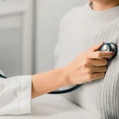 Un médecin écoute le cœur d'une patiente, cherchant un petit souffle au cœur.