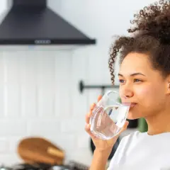 Donna sorseggia un bicchiere d'acqua, un rimedio naturale per la stitichezza.