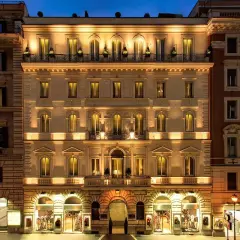 Edificio illuminato di notte, con negozi al piano terra, nel quartiere Esquilino a Roma.