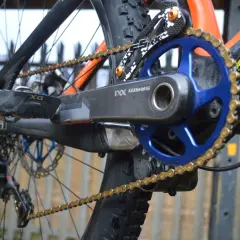 Close-up of a mountain bike's drivetrain, featuring a SRAM XX1 chain, blue chainring, and black crank arm.