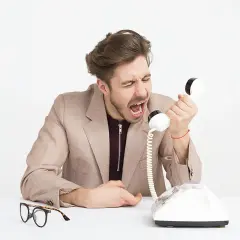 Mężczyzna krzyczy do telefonu, pokazując, co to egoizm. Obok leżą okulary.