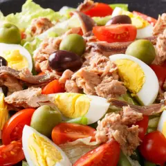 Ein appetitliches Salat Niçoise Rezept mit Thunfisch, Ei, Tomaten, Oliven und Sardellen auf knackigem Salat.