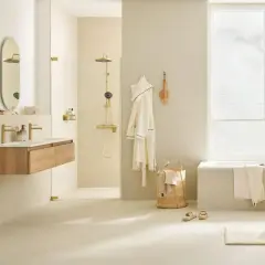 Helles, modernes Badezimmer mit cremefarbener Wandgestaltung. Goldene Armaturen und Duschkopf setzen Akzente. Die Farbgestaltung des kleinen Badezimmers ist beruhigend.