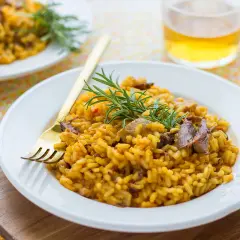 Delicioso arroz con secreto ibérico y setas, adornado con romero fresco. Un plato principal perfecto.