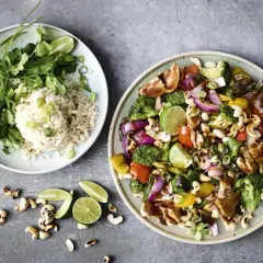 Två tallrikar med mat. En med ris, koriander och lime. Den andra med kyckling, grönsaker och cashewnötter, en perfekt enkel lunch.