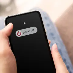 Dłoń trzyma telefon z widocznym przyciskiem "power off". Wygląda jakby telefon miał wejść w tryb awaryjny.