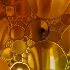 Gotas doradas y ámbar flotan juntas, creando un patrón hipnótico que te hace soñar con aceite.