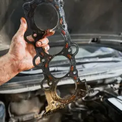 Brudna uszczelka pod głowicą, którą mechanik trzyma w ręku. Czas jej wymiany zależy od wielu czynników.
