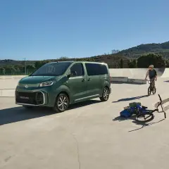 Grön Toyota Proace Verso parkerad vid en skatepark. En pappa och dotter med cyklar, en pojke på BMX.
