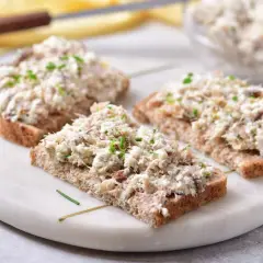 Trzy kromki ciemnego chleba z obfitym smarowidłem, czyli pasta z makreli i twarogu, posypana szczypiorkiem.