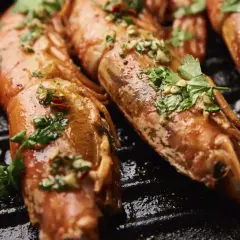 Gambas a la plancha jugosas y doradas, con perejil fresco y ajo picado, listas para disfrutar.