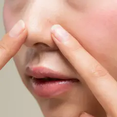 Dłonie dotykają nosa, ukazując pory i zaczerwienienie. Czy to nadmiar sebum?