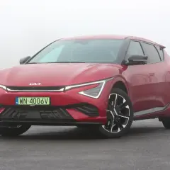 Czerwone Kia EV6 GT na mokrej drodze, w tle mgła.