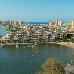 Widok na la Manga z plażą, budynkami mieszkalnymi i łodziami na wodzie.
