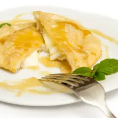 Seadas al miele, un dolce fritto ripieno di formaggio, irrorato di miele dorato e guarnito con menta fresca.