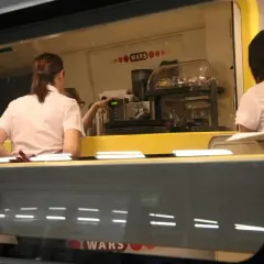 Wnętrze wagonu restauracyjnego z obsługą przygotowującą napoje.