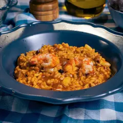 Un plato de paella mixta con gambas y arroz dorado, listo para disfrutar.