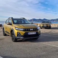 Dwa złote Dacia Sandero Stepway na tle morza i gór. Dwa modele, różne silniki, gotowe na przygodę.