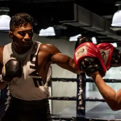 A boxer throws a powerful left hook in a boxing ring, his opponent ready to block.