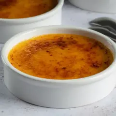 Dwa białe naczynia z pyszną, skarmelizowaną górą. Idealna crema catalana, gotowa do rozkoszowania się.