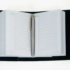 Eleganckie etui na notatnik służbowy z metalowym długopisem. Gotowe do zapisywania ważnych informacji.