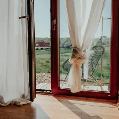 Jak upiąć za długie firanki? Węzeł na zasłonie przy oknie z widokiem na wieś.