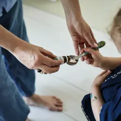 Mama podaje dziecku łyżeczkę z kroplami psychobiotyku. Dziecko z zaciekawieniem patrzy na podawany specyfik.