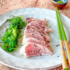 Tataki de bonito, finas lonchas de pescado rosado con semillas de sésamo, acompañadas de ensalada de algas.