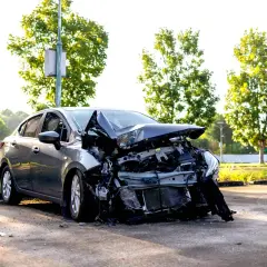 Voiture grise gravement accidentée, capot déformé. Un rappel de l'importance de l'assurance parking voiture.