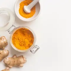Słoik z kurkumą w proszku, moździerz z przyprawą i korzenie imbiru. Turmeric co to? To złocisty skarb natury.