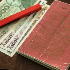 Książeczka mieszkaniowa z PRL-u, banknoty 5000 i 1000 zł oraz czerwony długopis.
