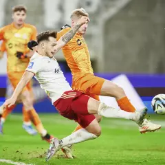Piłkarz Zagłębia Lubin walczy o piłkę z zawodnikiem ŁKS Łódź. Intensywna akcja na boisku.