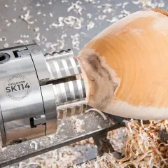 Mandrin de tour à bois fait maison, prêt à façonner un objet en bois. Copeaux de bois éparpillés.