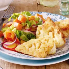 Knuspriges Blumenkohl Schnitzel mit einem bunten Salat aus Kürbis, Radieschen und roten Zwiebeln auf einem blumengemusterten Teller.