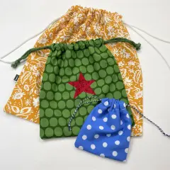 Trzy kolorowe torby DIY: żółta w kwiaty, zielona w kropki z czerwoną gwiazdą i niebieska w białe kropki.