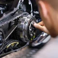 Mechanik sprawdza sprzęgło motocykla, zastanawiając się, czy można zmieniać biegi bez sprzęgła.