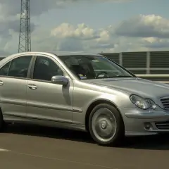 Srebrny Mercedes W203 2.2 CDI pędzi autostradą, chmury na niebie tworzą ciekawe kształty.