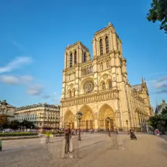Vue de la cathédrale Notre-Dame de Paris sous un ciel bleu, avec des passants fantomatiques sur le parvis. Un avis sur ce monument emblématique.