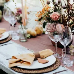Elegancko nakryty stół, idealny do organizacji wesela krok po kroku. Rustykalne dekoracje, kwiaty i świece tworzą ciepłą atmosferę.