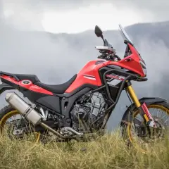 Rieju Aventura 500, lista para la aventura. Ficha técnica de esta moto trail roja y negra en un paisaje montañoso.