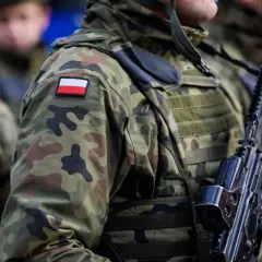 Żołnierze w kamuflażu, z polską flagą na ramieniu, gotowi do mobilizacji. Broń w rękach, czujność na twarzach.